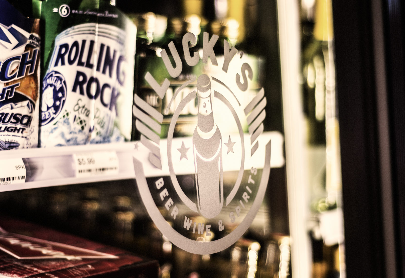 Luckys Liquors logo vinyl on cooler door highlighting retail interior design